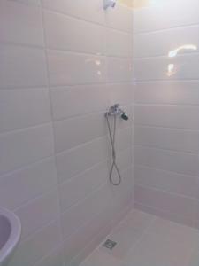 La salle de bains est pourvue d'une douche blanche avec un tuyau. dans l'établissement Maison d'Hôtes Ghalil, à Ouarzazate