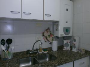 encimera de cocina con fregadero y armarios blancos en Departamento en Recoleta Santafesina en Santa Fe