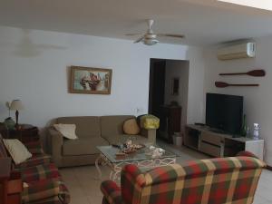 Casa 03 suites com ar. في بوزيوس: غرفة معيشة مع أريكة وتلفزيون