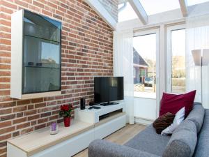 a living room with a brick wall and a television at Komfortwohnung Sonnenhain in Norderney