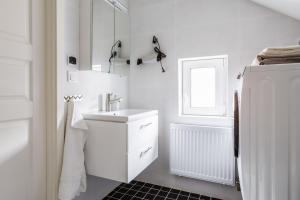 W białej łazience znajduje się umywalka i lodówka. w obiekcie Flores 3 w mieście Jönköping