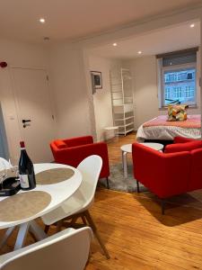 a living room with red chairs and a bed at Les Gîtes Du Palais in Dinant