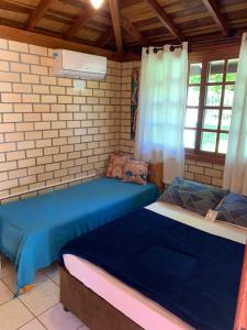 two beds in a room with two windows at Morada Quatro Elementos in Praia do Rosa
