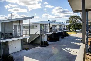 uma fila de casas com uma pessoa de pé na varanda em Peace Resorts - Jervis Bay Holiday Cabins in Sussex Inlet em Sussex inlet