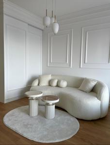 a white living room with a couch and two tables at Sky Residence West 65 Tower in Belgrade