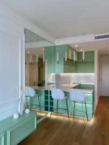 a kitchen with green cabinets and white stools at Sky Residence West 65 Tower in Belgrade