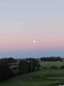 Une lune dans le ciel sur un champ vert dans l'établissement Casa de campo CLARA LUNA Sierra y Mar, à Punta Ballena