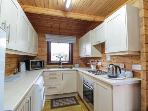 a kitchen with white cabinets and a wooden ceiling at Moyle Lodge in Dalbeattie