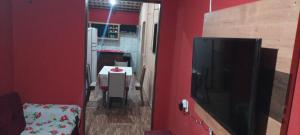 sala de estar con pared roja y TV en Casa Friozinho da serra en Guaramiranga