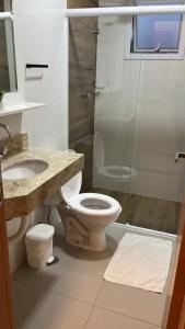 La salle de bains est pourvue de toilettes et d'une douche en verre. dans l'établissement Apartamento Jardins Ubatuba, à Ubatuba