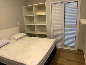 a small bedroom with a bed and shelves at Apartamento Jardins Ubatuba in Ubatuba