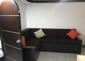 Hotel magallanes con cocineta 100 Metros de playa في أكابولكو: أريكة سوداء مع وسادتين في غرفة