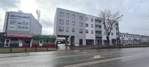 una calle urbana vacía con un edificio blanco en 68 - Apartamenty Siedlce - Nowy apartament w centrum przy ul. 3 Maja 51a, en Siedlce