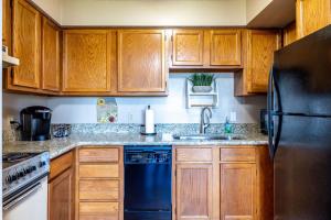a kitchen with wooden cabinets and a black refrigerator at WOW Views!!-Mountain Escape-Outdoor Pool-Close to Downtown-WiFi-Cable-Private Balcony in Gatlinburg