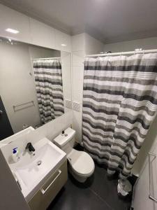 a bathroom with a sink and a toilet and a shower curtain at Apartamento junto a la playa - Vistas Increíbles in Coquimbo