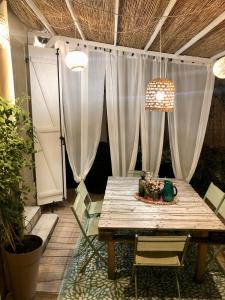 a wooden table and chairs in a patio with curtains at Le Nid Cosy in Bordeaux