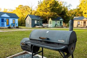 a grill sitting on a bench in a field with houses at Experience Tiny Living, in Cape Charles, Va in Cape Charles