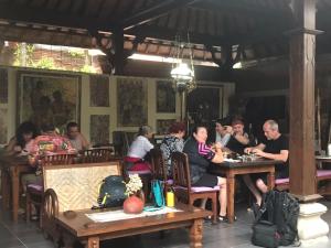 a group of people sitting at tables in a restaurant at Nirvana Pension in Ubud