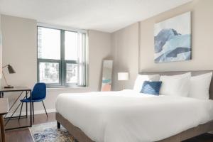 a bedroom with a large white bed and a blue chair at Kasa Magnificent Mile Chicago in Chicago