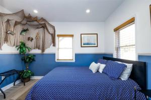 a blue and white bedroom with a bed and two windows at Pet Friendly Tiny Livin 3min from Cape Charles in Cape Charles