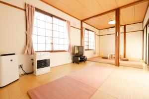 Guest House Matsuyoshi في بحيرة تويا: غرفة فارغة فيها تلفزيون وغرفة فيها نوافذ