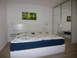 a bedroom with a white bed with a blue blanket at Resort Orther Reede, Fehmarn-Orth in Orth