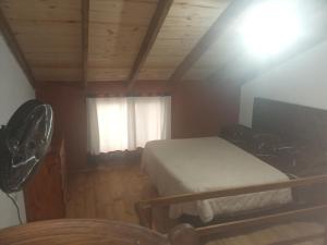 1 dormitorio con 1 cama y ventana con ventilador en Los jilgeros en Santa Rosa de Calamuchita
