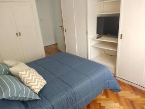 1 dormitorio con 1 cama azul y TV en Departamento en Recoleta en Buenos Aires