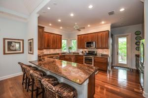 a kitchen with a large island with bar stools at Casa Mariposa - Luxury Butterfly Garden Steps to Pine Ave PoolSpa Bikes 4 Houses to Beach in Anna Maria