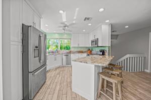 a kitchen with white cabinets and a stainless steel refrigerator at La Buena Vida - Bright Beachy Canal Front Steps to Beach PoolSpa Dock Beach Gear Dogs OK in Anna Maria