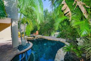a swimming pool in a yard with palm trees at La Buena Vida - Bright Beachy Canal Front Steps to Beach PoolSpa Dock Beach Gear Dogs OK in Anna Maria