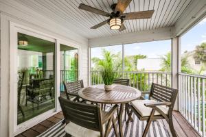 a porch with a table and chairs and a ceiling fan at Found Your Sol Mate Gorgeous Home w Pool Spa Steps to Bean Point Dogs OK in Anna Maria