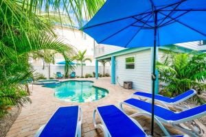 a patio with chairs and an umbrella and a pool at Found Your Sol Mate Gorgeous Home w Pool Spa Steps to Bean Point Dogs OK in Anna Maria