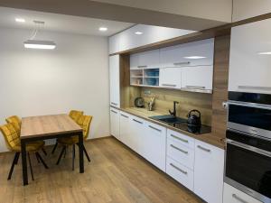 a kitchen with white cabinets and a wooden table at Wellness & Spa Apartments Lipno - Frymburk in Frymburk
