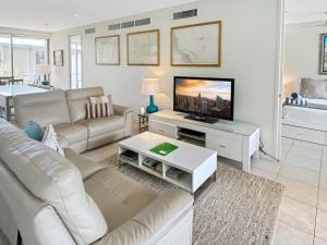 a living room with a couch and a flat screen tv at Serenity in Picnic Bay