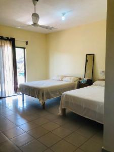 1 Schlafzimmer mit 2 Betten, einem Fenster und einem Spiegel in der Unterkunft Habitaciones Chalo in Garita