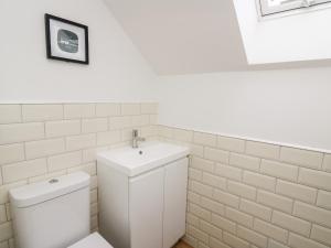 a white bathroom with a toilet and a sink at Ysgoldy Brynwyre in Llanrhystyd