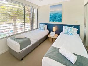 two beds in a room with a window at Serenity in Picnic Bay