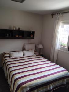 a bedroom with a large striped bed with a window at Tiempo de Paz in Guaymallen