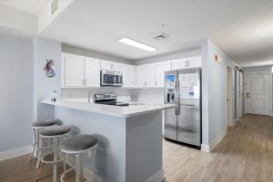 una cocina con armarios blancos y una barra con taburetes en Brand New Calypso Resort Tower 3! Sleeps 9! Free Beach Chair Service! by Dolce Vita Getaways PCB en Panama City Beach