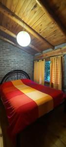 1 dormitorio con 1 cama con una manta colorida en Bosque Nativo en Lago Puelo