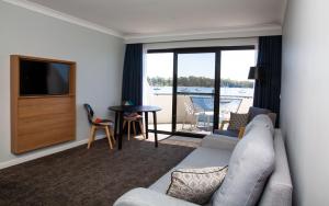 a living room with a couch and a television at The Esplanade Motel in Batemans Bay