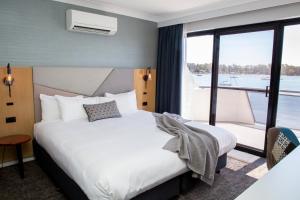 a hotel room with a bed and a large window at The Esplanade Motel in Batemans Bay