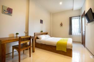 a bedroom with a bed and a desk and a television at K Hostel Seminyak in Seminyak