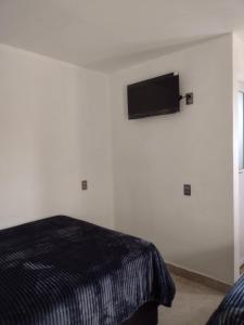 a bedroom with a bed and a flat screen tv on the wall at Hotel OCLAS in Chignahuapan