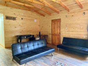 a living room with black leather couches and a wooden wall at Cabaña Loncoche, villarrica in Loncoche