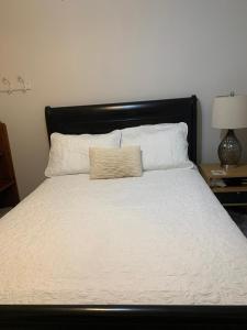 a bed with a black headboard and white sheets and pillows at Room near Airport/ Cerca del Aeropuerto in Santiago Este