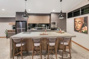 a kitchen with a large island with chairs around it at Villa Thirty One - Balinese inspired Escape in Cairns