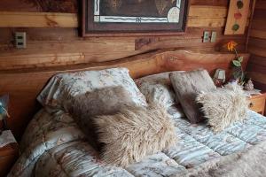 Una cama en una cabaña de madera con almohadas. en Fabulosa y mágica casa en Pingueral, en Tomé