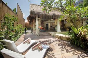 un patio del complejo con sillas blancas y árboles en Villa Tatu by Optimum Bali Villas, en Canggu
